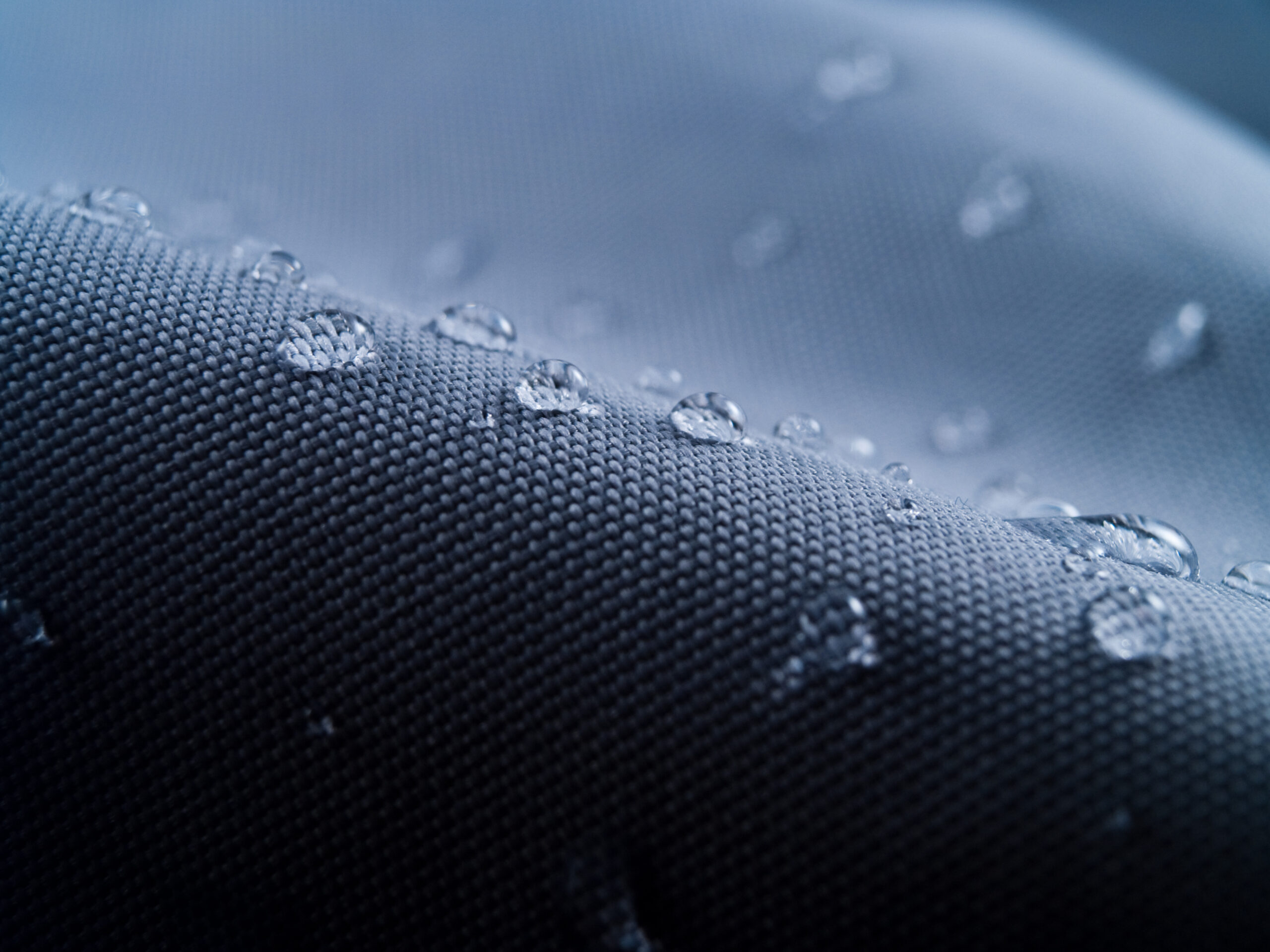 Macro shot of water rain drops on waterproof textile jacket.